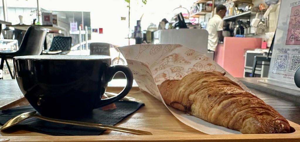Coffee and croissant on wooden board