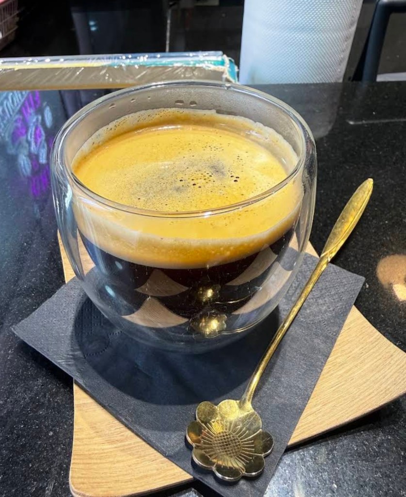Espresso in double-wall glass with gold flower spoon